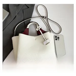 Detail of white lychee leather tote bag with dark red lining and gold bottom rivets