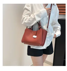 Close-up of brick red pebble grain leather texture and silver square buckle on bucket bag