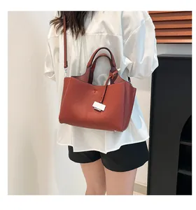 Detail of brick red bucket bag with lychee texture and metallic accent on shoulder strap