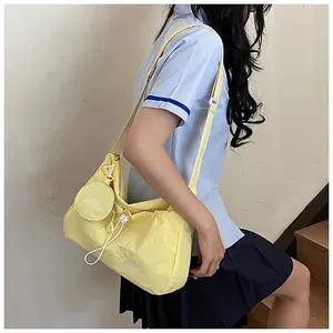 Detail of light yellow nylon tote bag featuring pleated texture and mini coin purse