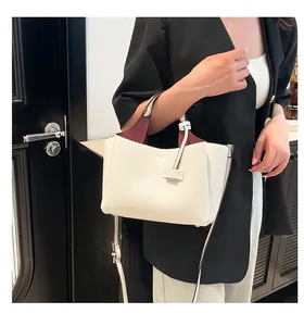 Detail of white lychee leather handbag with T-shaped logo and burgundy interior lining