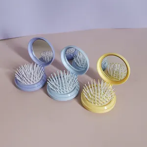 Makroaufnahme der faltbaren Haarbürste mit Spiegel in Pastelllila, Blau und Gelb