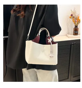 Detail of soft off-white leather bucket bag with burgundy interior and metal hooks
