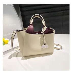 Close-up of pebble leather bucket bag with cream exterior and burgundy interior lining