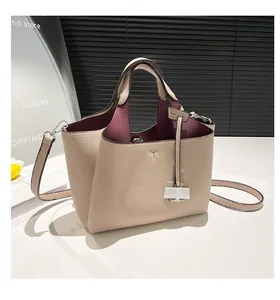 Close-up of beige lychee grain leather bucket bag with burgundy lining and T-logo detail