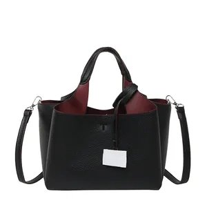 Premium black pebbled leather bucket bag with top handle and contrasting red interior