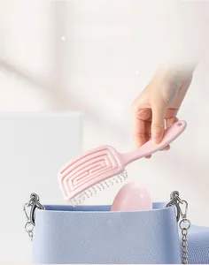 Pink mini spiral vent hairbrush being placed into a small blue chain handbag
