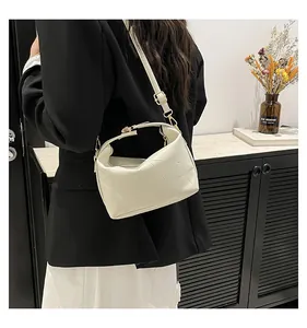 Détail du sac seau crème montrant la texture grainée et la boucle en métal doré