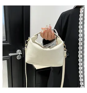 Détail du sac seau en cuir crème montrant le grain de litchi et les crochets dorés