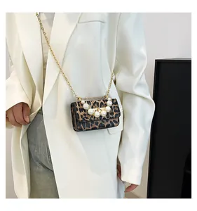 Detail of leopard print jelly bag featuring pearl handle and gold chain strap
