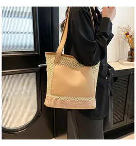 Detail of woven straw tote bag featuring a pink base, leather pocket, and long straps
