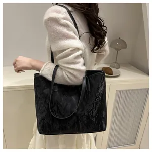 Détail d'un grand sac cabas noir avec texture plissée et fines anses en cuir