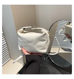 Détail du sac seau crème avec surpiqûres géométriques et texture cuir grainé