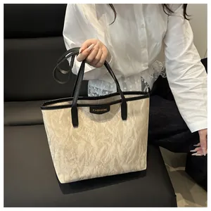 Détail du sac cabas beige avec texture marbrée et finitions en cuir noir élégant