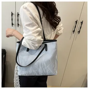 Détail du sac cabas bleu clair à texture froissée avec anses noires et reflets argentés