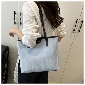Détail du sac fourre-tout plissé bleu clair avec garniture en cuir noir et logo doré