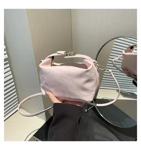 Détail du sac seau rose clair avec coutures géométriques et boucle en métal doré