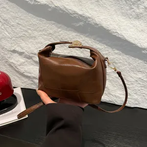 Sac seau marron en similicuir avec poignée supérieure et fermoir doré sur socle pierre