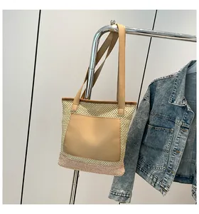 Detail of woven straw tote bag featuring pink contrast base and faux leather pocket