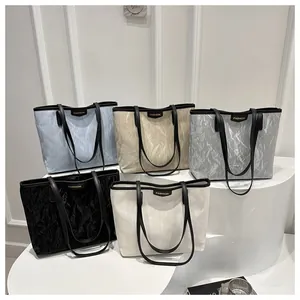 Détail de cinq sacs cabas plissés aux tons pastels avec doubles anses noires
