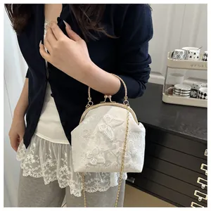 Close-up of white lace tote bag featuring butterfly embroidery and vintage gold metal clasp