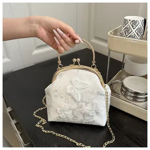 Close-up of white lace handbag featuring 3D butterfly embroidery and gold metal hardware