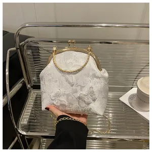 Detail of white lace embroidery handbag with floral butterfly patterns and gold metal clasp