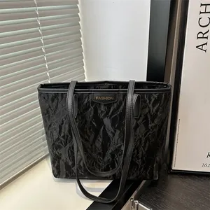 Sac fourre-tout noir unique avec texture froissée et logo doré sur fond élégant