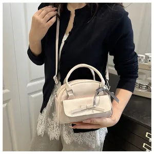 Detail of cream white handbag with bow tie ribbon and adjustable shoulder strap