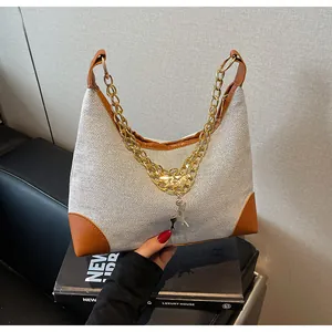 Close-up of woven tote bag with brown leather trim, gold chain, and deer pendant charm