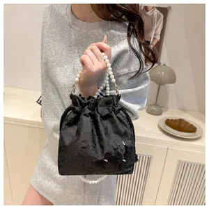 Detail of black satin bucket bag with floral jacquard texture and faux pearl strap