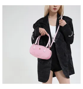 Detail of pink woven texture crossbody bag with gold logo shown on model with black blazer
