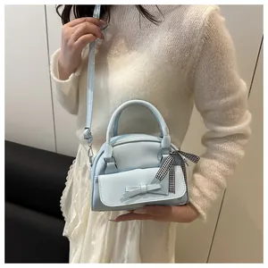 Close-up of light blue mini handbag with leather bow and plaid ribbon detail