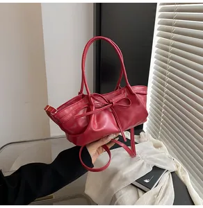 Detail of red pleated bucket bag with bow ornament and detachable shoulder strap