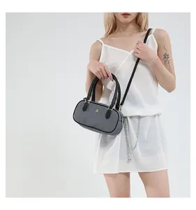 Detail of a minimalist grey textured cylindrical pillow bag with black top handles