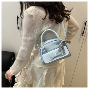 Detailed side view of light blue handbag with bow ornament worn by a fashion model