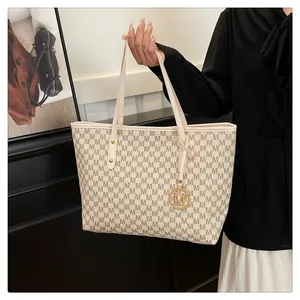 Close-up of printed tote bag featuring M-pattern jacquard and gold metal charm