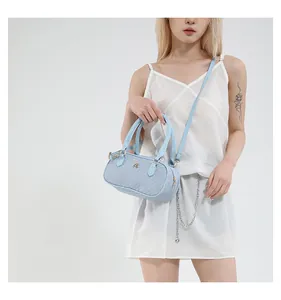 Detailed view of light blue tweed bucket bag with gold metal logo and handle