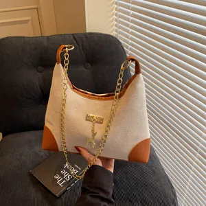Large beige canvas tote bag with brown leather trim and golden deer pendant detail