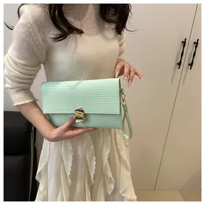Detail of light green crossbody bag featuring gold geometric lock and textured surface