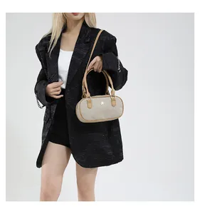 Detail of a beige woven pillow bag with brown leather trim held by a model in a black suit