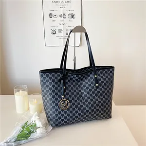 Large capacity printed tote bag with M-pattern and metal charm in a modern setting