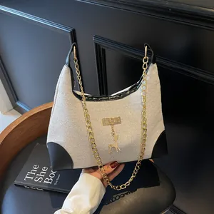 Borsa tote chic in tela beige e pelle nera con catena dorata e ciondolo a forma di cervo