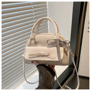 Detail of cream bow handbag with checkered ribbon on handle in a lifestyle setting