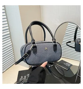 Detail of blue denim and black leather pillow bag with gold metal logo and strap