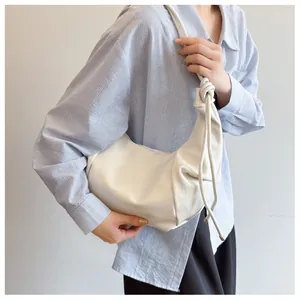 Side view of cream PU leather hobo bag with decorative knot detail on the shoulder strap