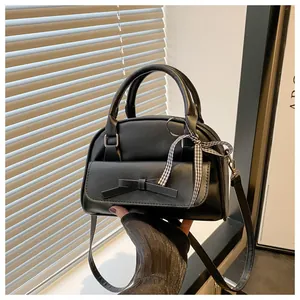 Close-up of black PU leather handbag with decorative bow and black-white checkered ribbon
