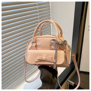 Detail of light pink shell-shaped handbag with decorative bow and checkered ribbon