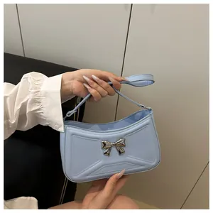 Gros plan du sac à main bleu clair avec nœud argenté et surpiqûres élégantes