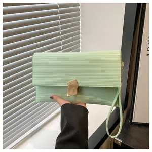 Detail of mint green envelope clutch with textured stripes and gold metal clasp